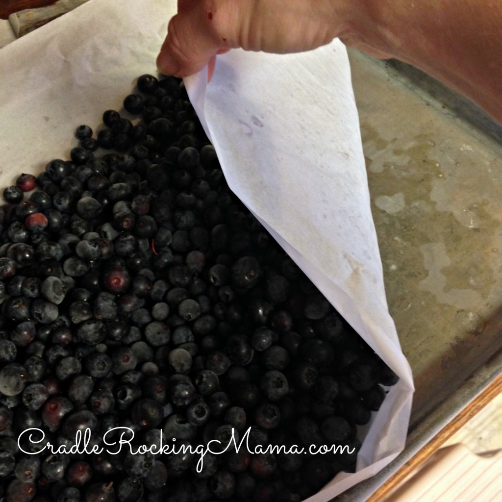 Pulling the corner of the parchment paper up to loosen the blueberries CradleRockingMama.com